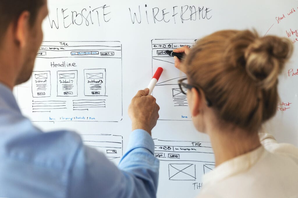 Marketing drawing a website wireframe on a whiteboard